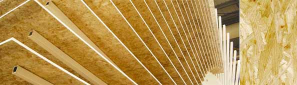 Stos płyt OSB ułożonych pionowo z widoczną strukturą drewna i elementami dystansowymi w kształcie profili kwadratowych.